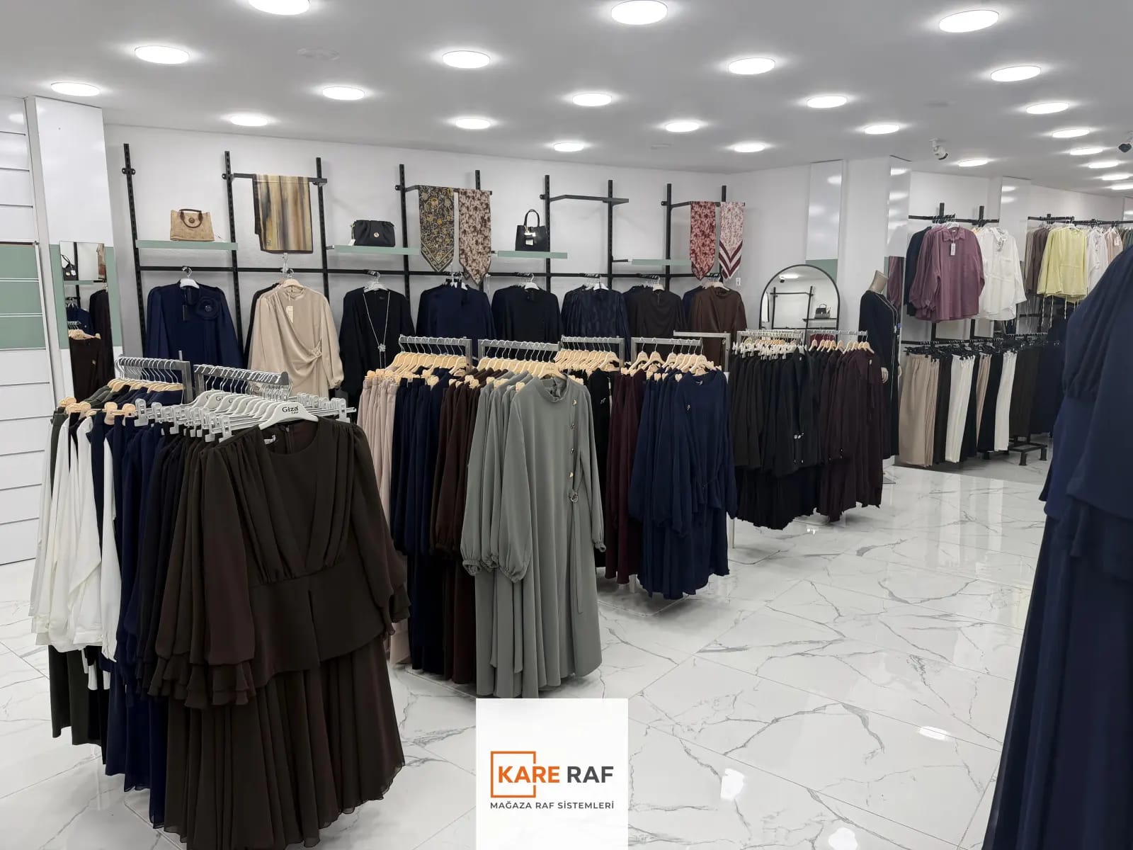 Armira mağazasında raflı duvar askıları, çanta ve eşarp teşhiri, zeminde ayaklı askılar ve elbiseler