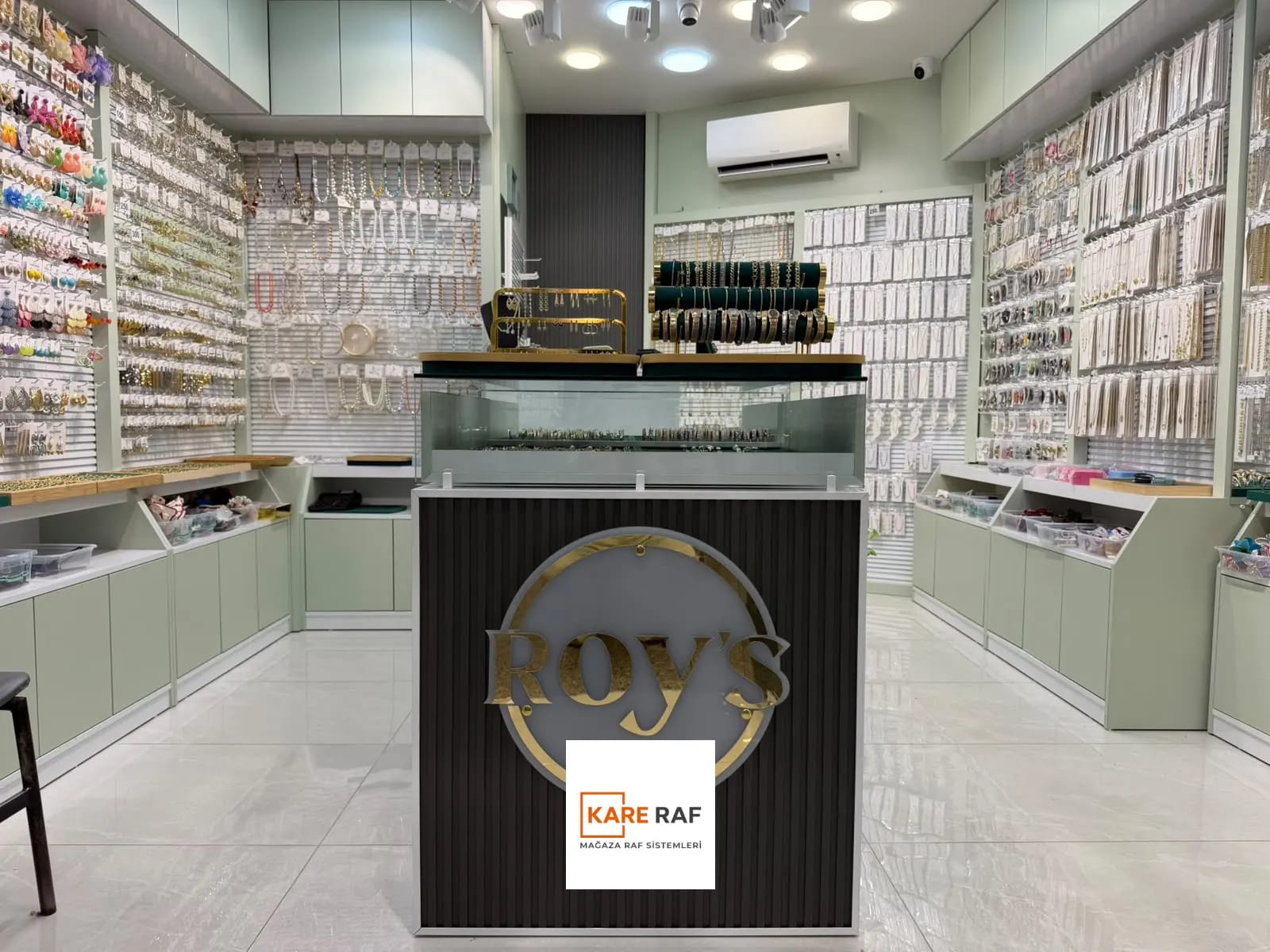 Tahtakale'deki Roy's Accessories bijuteri mağazası: ortada logolu teşhir standı, iki yanda kanallı panolu takı duvarları