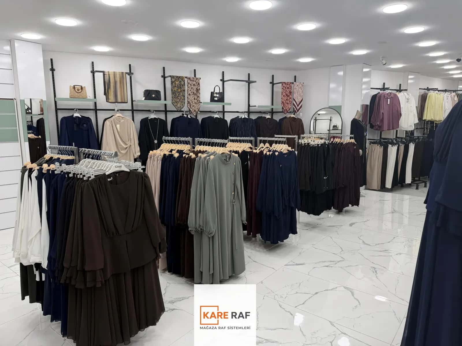 Armira mağazasında raflı duvar askıları, çanta ve eşarp teşhiri, zeminde ayaklı askılar ve elbiseler