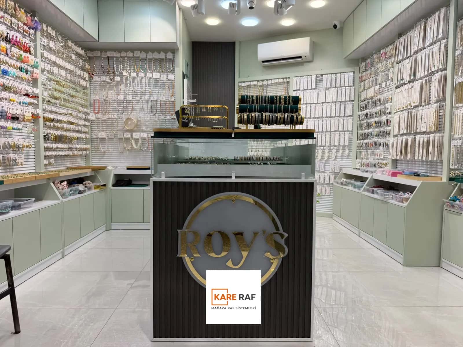 Tahtakale'deki Roy's Accessories bijuteri mağazası: ortada logolu teşhir standı, iki yanda kanallı panolu takı duvarları