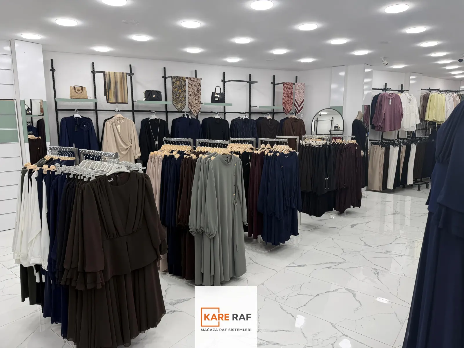 Armira mağazasında raflı duvar askıları, çanta ve eşarp teşhiri, zeminde ayaklı askılar ve elbiseler