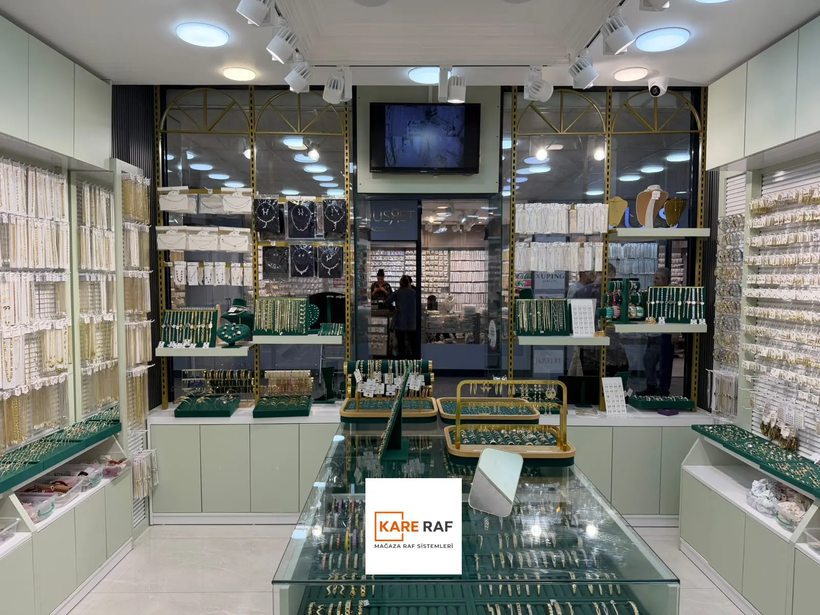 Roy's Accessories'te cam üstlü teşhir tezgâhı, kanallı pano duvarlar ve adaçayı yeşili alt dolaplar